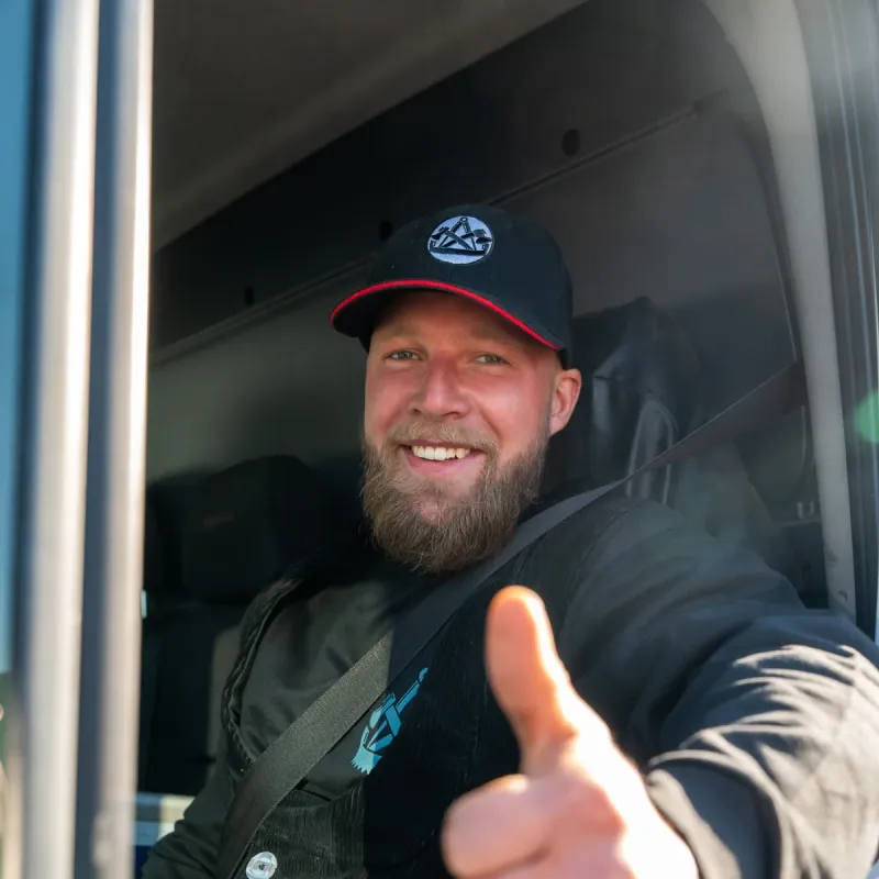 Mitarbeiter der Zimmerei Der Holzprofi zeigt Daumen hoch aus dem Mercedes-Sprinter — gebrandete Zimmertracht der Holzprofi-Crew sichtbar