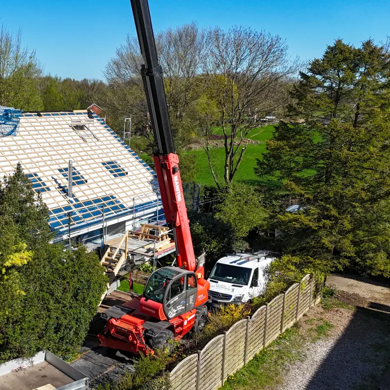 Roter Manitou MRT 2150 Teleskoplader der Zimmerei Der Holzprofi mit ausgefahrenem Ausleger beim Dachaufbau